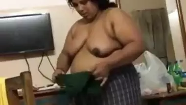 Fat Indian woman with big belly walks around the house with naked boobs